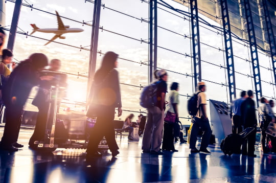 a crowd of people walk through a busy airport