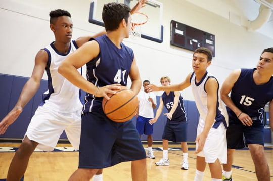 a group of teens play basketball in a gym